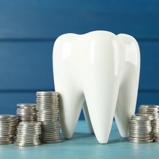 A large model tooth surrounded by silver metal coins