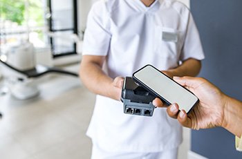 A woman using her smart phone to pay the cost of a root canal