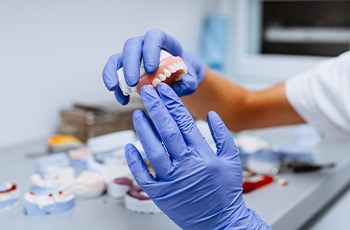 Gloved hands holding denture at dental lab