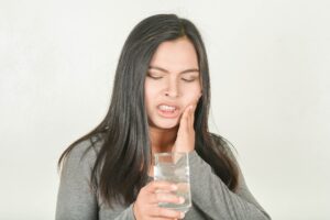 Woman experiencing tooth sensitivity from drinking water